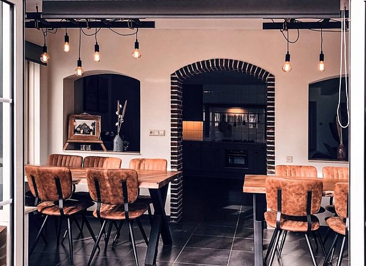 Hinterer Garten und Terrasse des Ferienhauses in De Cocksdorp, Texel, mit grossen Rasenflaechen.