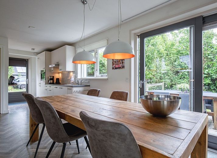 Gezellige eetruimte in Blommetjes Buiten vakantiehuis, De Cocksdorp Texel, met houten tafel en uitzicht op terras.