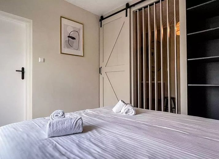 Achtertuin van Huisje in De Cocksdorp, vakantiehuis in Texel, met groene grasvelden en zonovergoten dak.