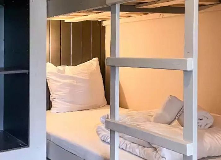 Sfeervolle slaapkamer in Huisje in De Cocksdorp, Texel, met houten lambrisering en zachte verlichting.