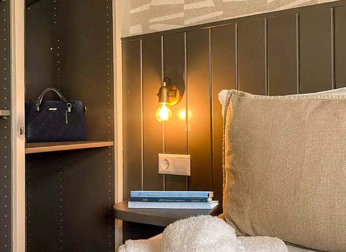 Sfeervolle slaapkamer in Huisje in De Cocksdorp, Texel, met houten lambrisering en zachte verlichting.