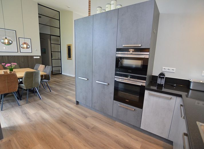 Bright living room of Orchismient 49 vacation home in De Koog, Texel with views of greenery and spacious seating area.