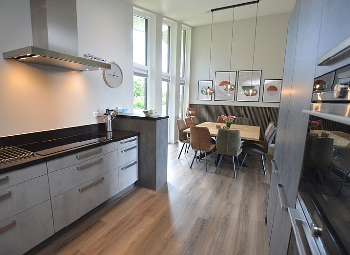 Bright living room of Orchismient 49 vacation home in De Koog, Texel with views of greenery and spacious seating area.