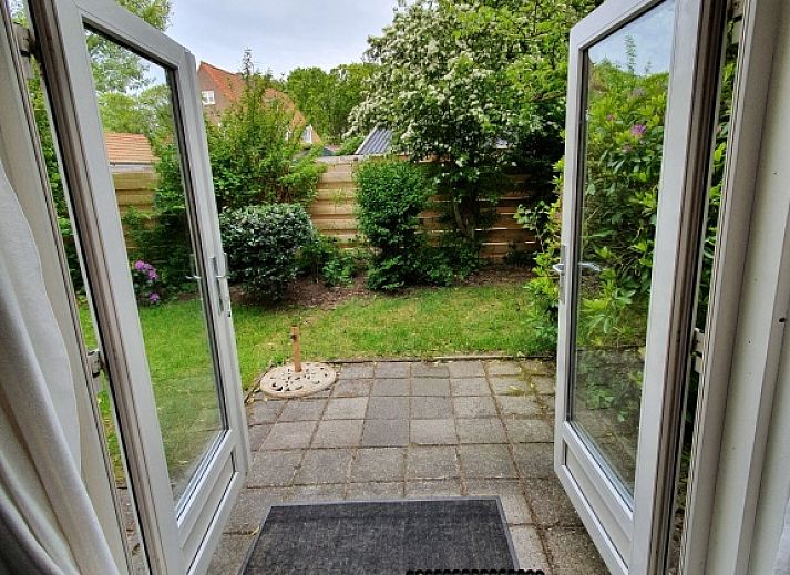 Cozy living room in Huisje Quirijn, De Koog Texel with colorful curtains and French doors to the garden.