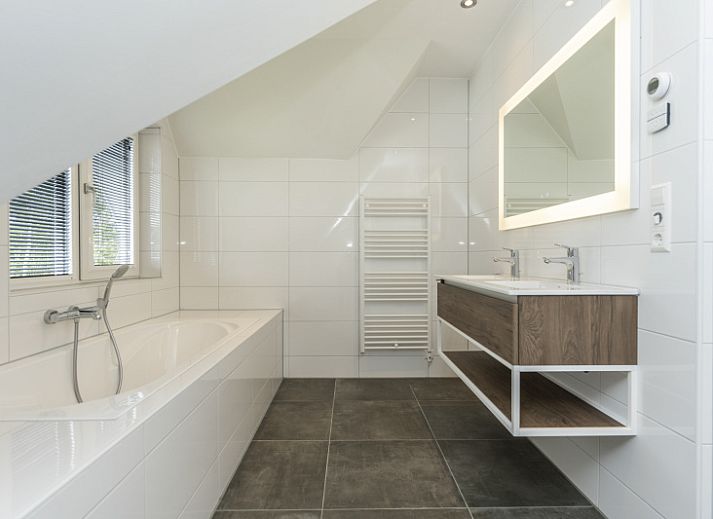 Stylish living room of Villa 17 in De Koog, Texel with open kitchen and garden view for a comfortable stay.