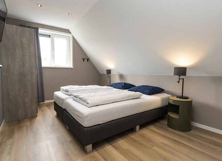 Stylish living room of Villa 17 in De Koog, Texel with open kitchen and garden view for a comfortable stay.