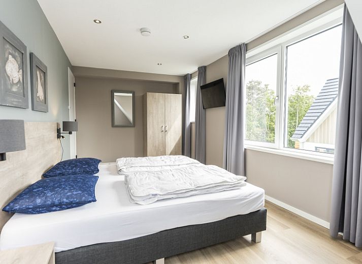 Stylish living room of Villa 17 in De Koog, Texel with open kitchen and garden view for a comfortable stay.