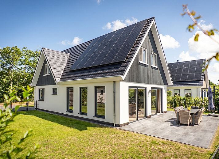 Stylish living room of Villa 17 in De Koog, Texel with open kitchen and garden view for a comfortable stay.