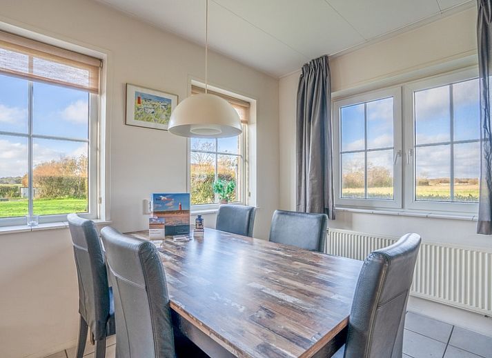 Cozy living room in Maaikeduinweg 13 vacation home, De Koog, Texel with comfortable seating area and garden view.