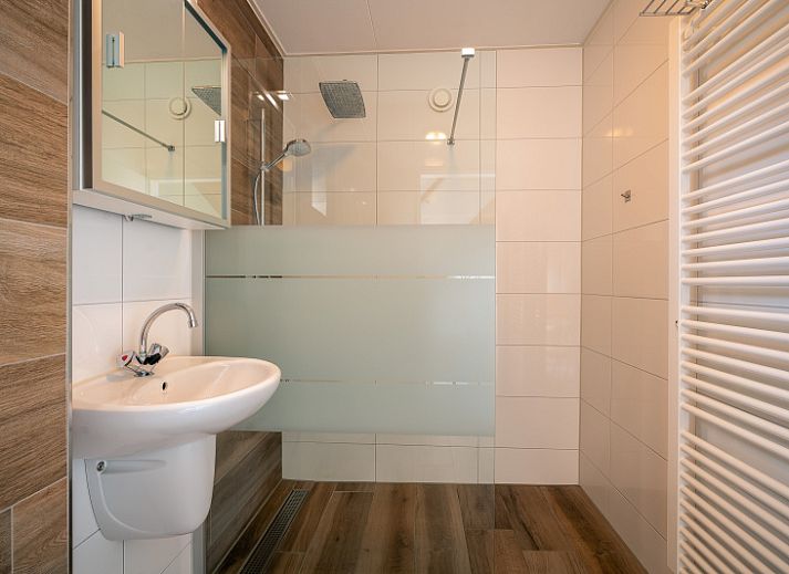 Cozy living room in Maaikeduinweg 13 vacation home, De Koog, Texel with comfortable seating area and garden view.