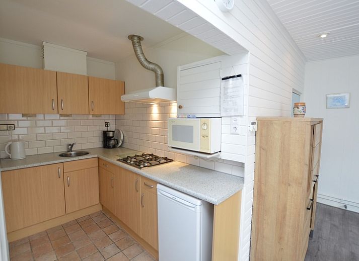 Modern living room in vacation home Plevierstraat 18, De Koog, Texel with comfortable seating area and wooden cupboard.