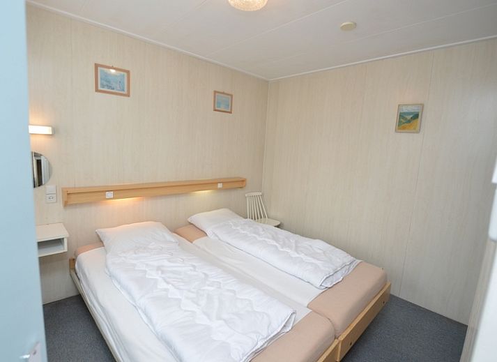 Modern living room in vacation home Plevierstraat 18, De Koog, Texel with comfortable seating area and wooden cupboard.