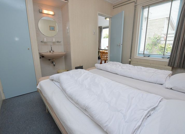 Modern living room in vacation home Plevierstraat 18, De Koog, Texel with comfortable seating area and wooden cupboard.