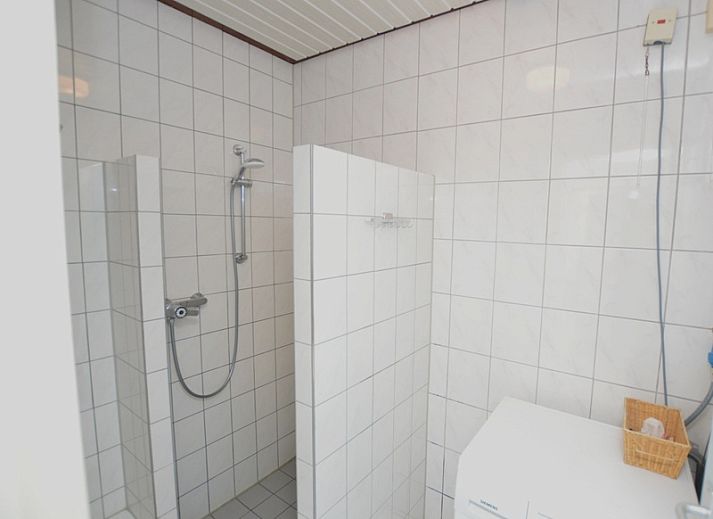 Modern living room in vacation home Plevierstraat 18, De Koog, Texel with comfortable seating area and wooden cupboard.