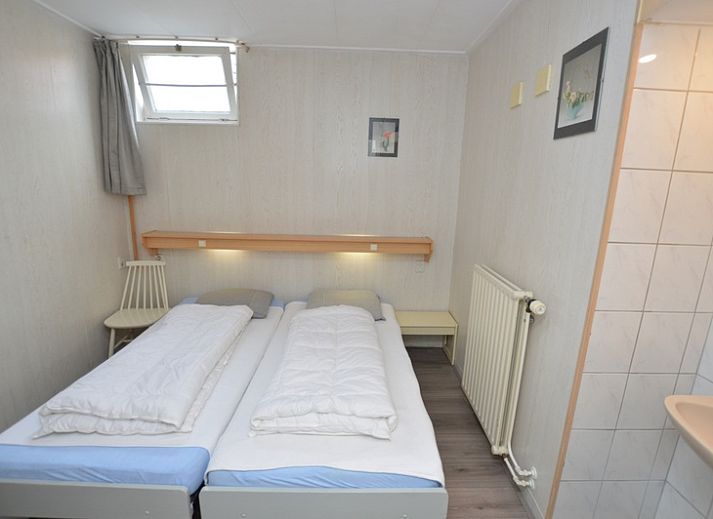 Cozy sitting area in Plevierstraat 18 vacation home, De Koog, Texel with sofa, armchairs and decorative flowers.