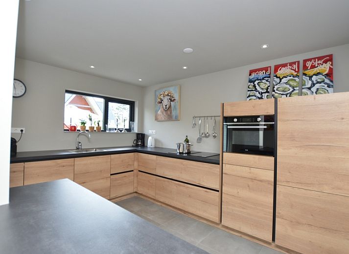 Gemuetliches Wohnzimmer in der Ruijslaan 73, De Koog, Texel, mit bequemen Sofas und grossen Fenstern.