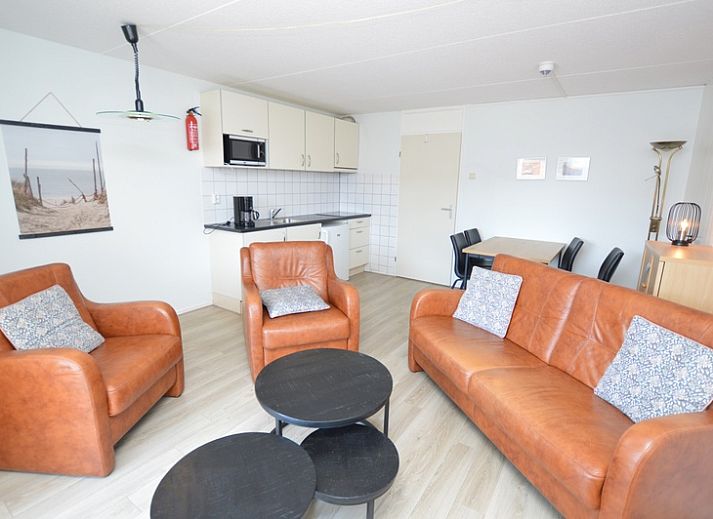 Gemuetliche Sitzecke im Motel Texel - Apartment 208/1L, De Koog, Texel, mit bequemen Ledersofas und einer offenen Kueche.
