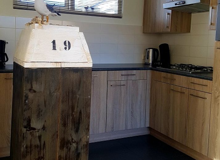 Cozy living room of vacation home De Anemoon in De Koog, Texel, overlooking green garden.