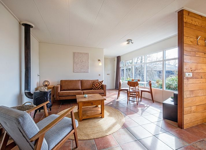 Ferienhaus De Zonneweelde in De Koog, Texel, umgeben von ueppiger Natur und Sonnenlicht auf der Terrasse.