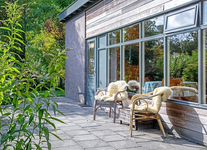 Ferienhaus De Zonneweelde in De Koog, Texel, umgeben von ueppiger Natur und Sonnenlicht auf der Terrasse.