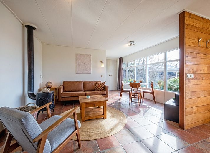 Veranda des Ferienhauses De Zonneweelde in De Koog, Texel, mit gruener Umgebung und Sitzgelegenheiten.