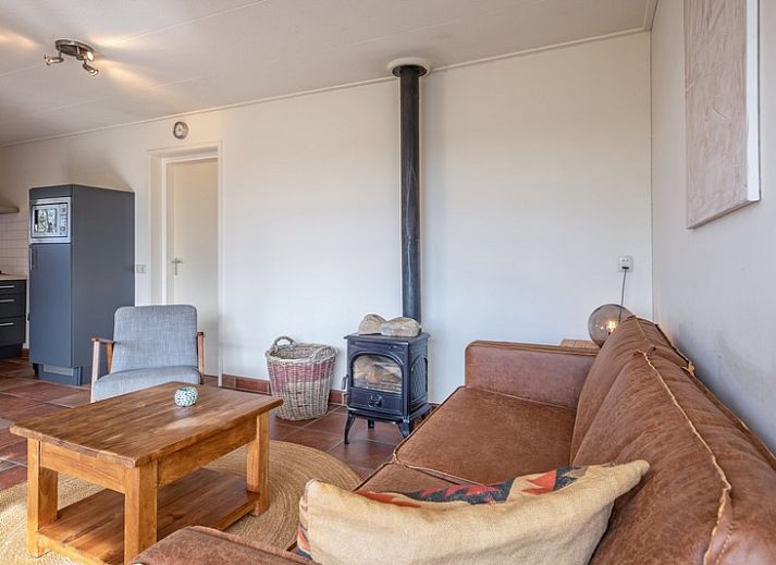 Veranda des Ferienhauses De Zonneweelde in De Koog, Texel, mit gruener Umgebung und Sitzgelegenheiten.