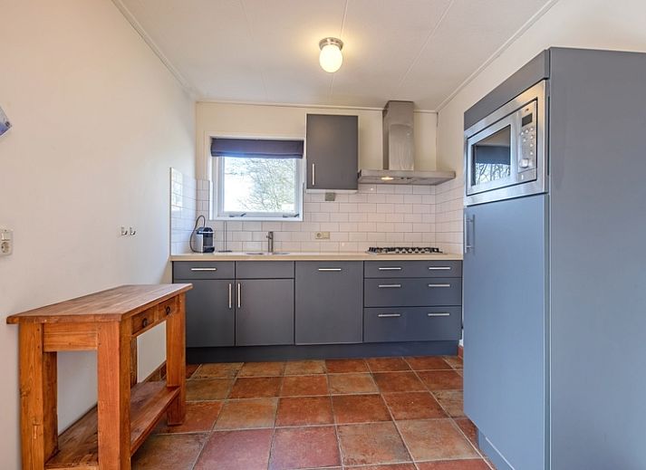 Veranda des Ferienhauses De Zonneweelde in De Koog, Texel, mit gruener Umgebung und Sitzgelegenheiten.