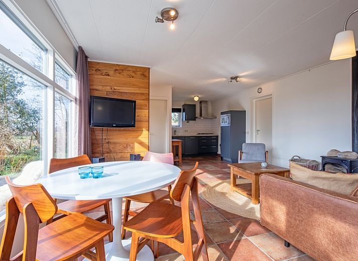 Veranda des Ferienhauses De Zonneweelde in De Koog, Texel, mit gruener Umgebung und Sitzgelegenheiten.