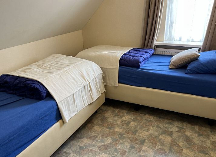 Cozy living room of Koetshuis vacation home in De Koog, Texel, with comfortable sofas and a television for relaxation.