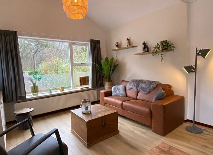 Gemuetliches Wohnzimmer des Ferienhauses Jutter in De Koog, Texel. Gemuetliche Sitzecke mit Blick auf die gruene Umgebung.