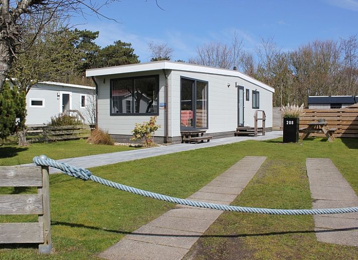 Das Chalet Bregkoog 208 in De Koog, Texel, bietet ein modernes Aeusseres mit grossen Fenstern und einer gruenen Umgebung.