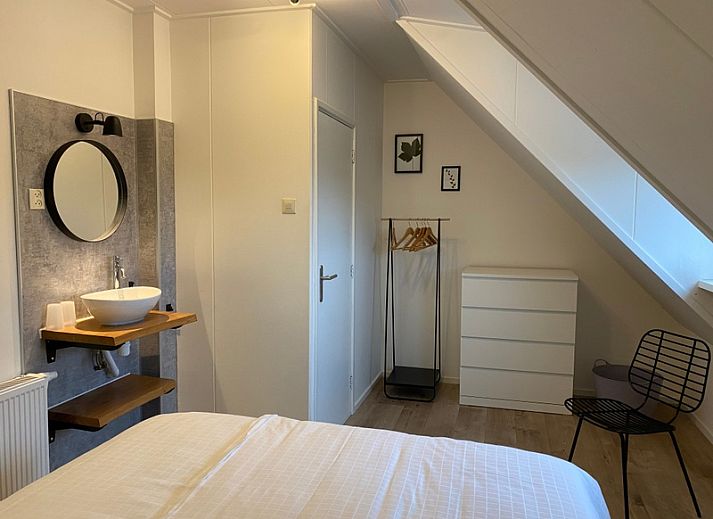 Cozy bedroom in De Boomleeuwerik vacation home, De Koog, Texel with green wall and comfortable beds.