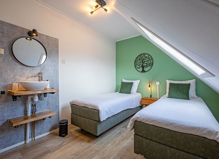 Cozy bedroom in De Boomleeuwerik vacation home, De Koog, Texel with green wall and comfortable beds.