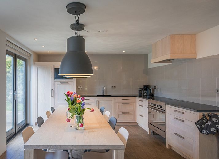Moderne Kueche im Ferienhaus Orchismient 24, De Koog, Texel, mit grossem Esstisch und stilvoller Beleuchtung.