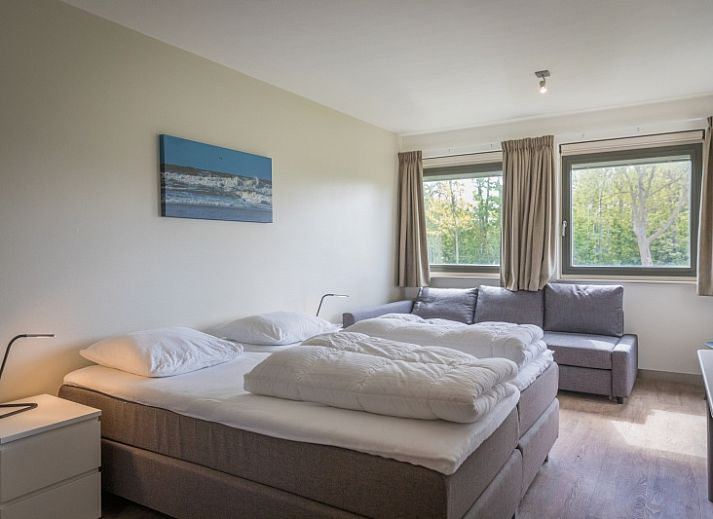 Gemuetlicher Essbereich im Ferienhaus Orchismient 24, De Koog, Texel, mit Blumen auf dem Tisch und Haengelampen.