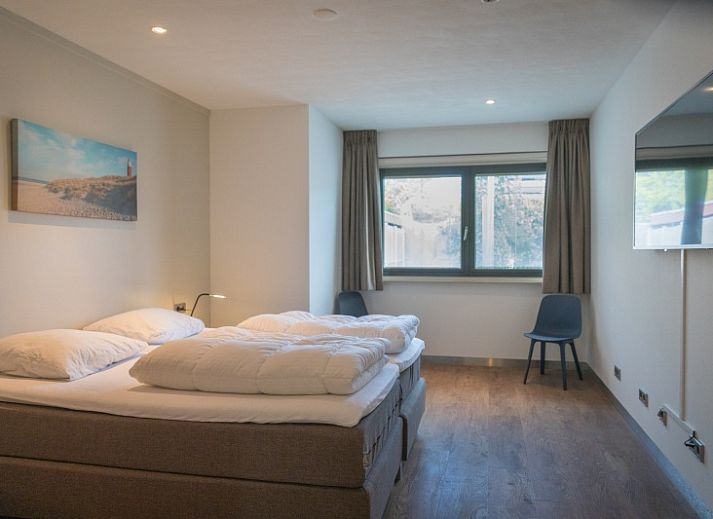 Gemuetlicher Essbereich im Ferienhaus Orchismient 24, De Koog, Texel, mit Blumen auf dem Tisch und Haengelampen.