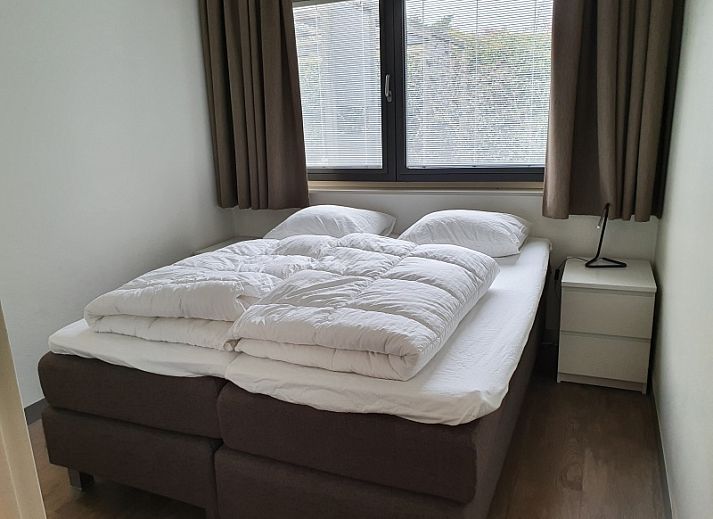 Gemuetliches Wohnzimmer in Orchismient 24, De Koog, Texel, mit Sofa und Kuestenlandschaft an der Wand.