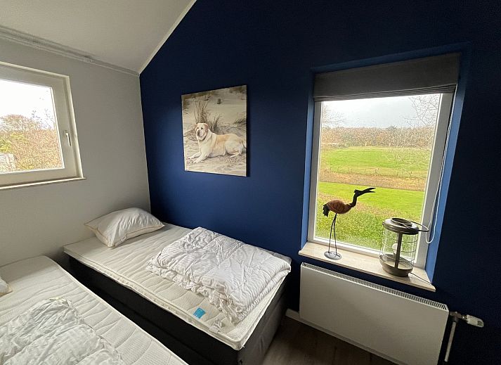 Stijlvolle woonkamer van De Duinven in De Koog, Texel, met uitzicht op de tuin, perfect voor familiebijeenkomsten.