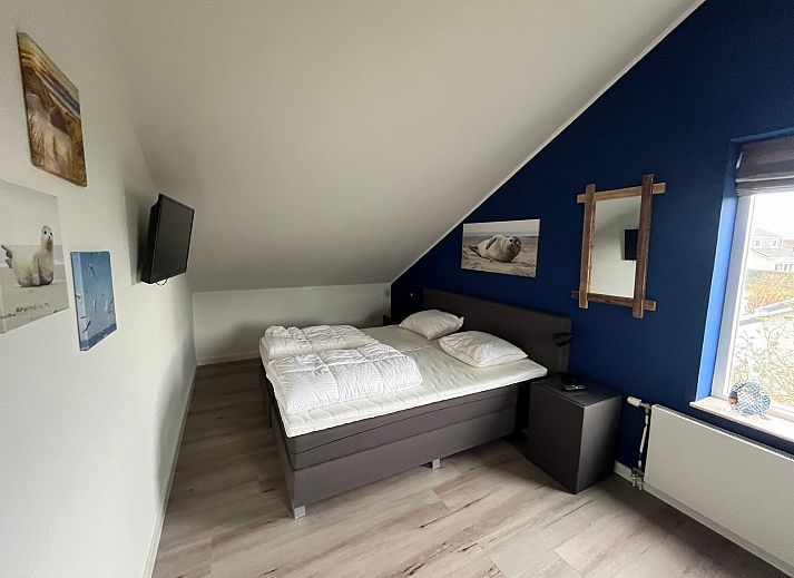 Stijlvolle woonkamer van De Duinven in De Koog, Texel, met uitzicht op de tuin, perfect voor familiebijeenkomsten.