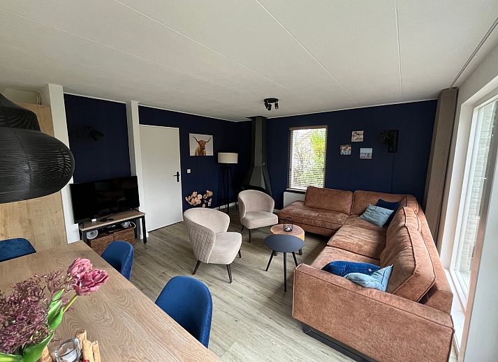 Stijlvolle woonkamer van De Duinven in De Koog, Texel, met uitzicht op de tuin, perfect voor familiebijeenkomsten.