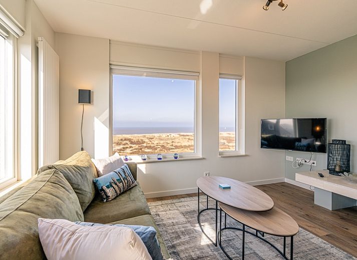 Wohnung Juliana 150 Zeezicht in De Koog Texel, helles Wohnzimmer mit Panoramablick auf Meer und Duenen.