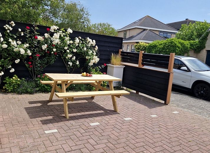 Exterior of Holiday home Duinzee Texel in De Koog with sunny terrace and colorful flowers.