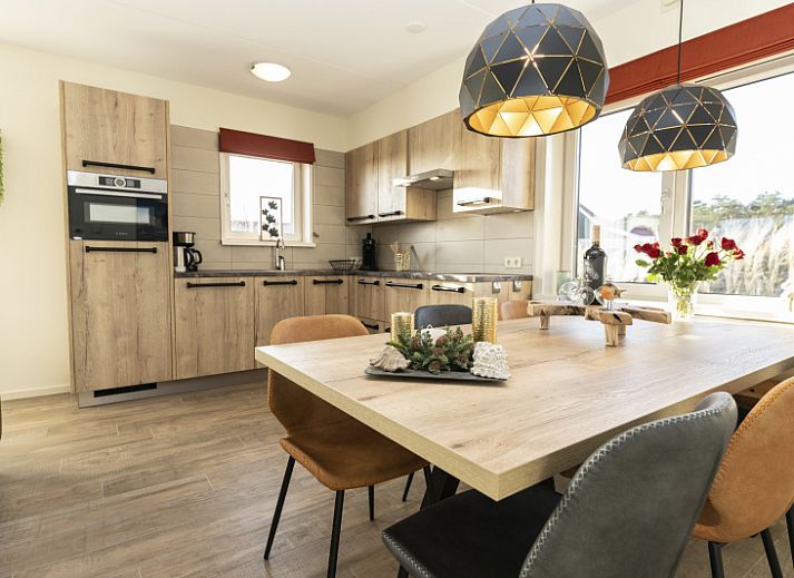 De Abeel vacation home with thatched roof in De Koog, Texel, surrounded by red flowers and dunes.
