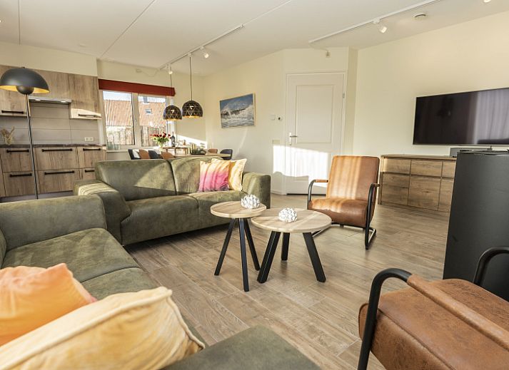 De Abeel vacation home with thatched roof in De Koog, Texel, surrounded by red flowers and dunes.