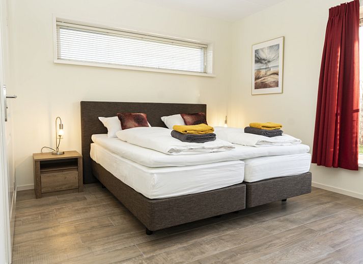 De Abeel vacation home with thatched roof in De Koog, Texel, surrounded by red flowers and dunes.