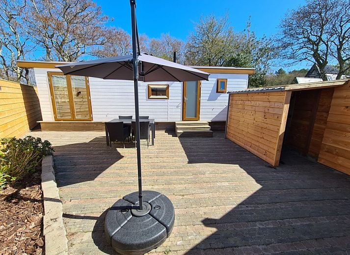 Veranda of Chalet Out and Home in De Koog, Texel, with wooden fence and parasol.
