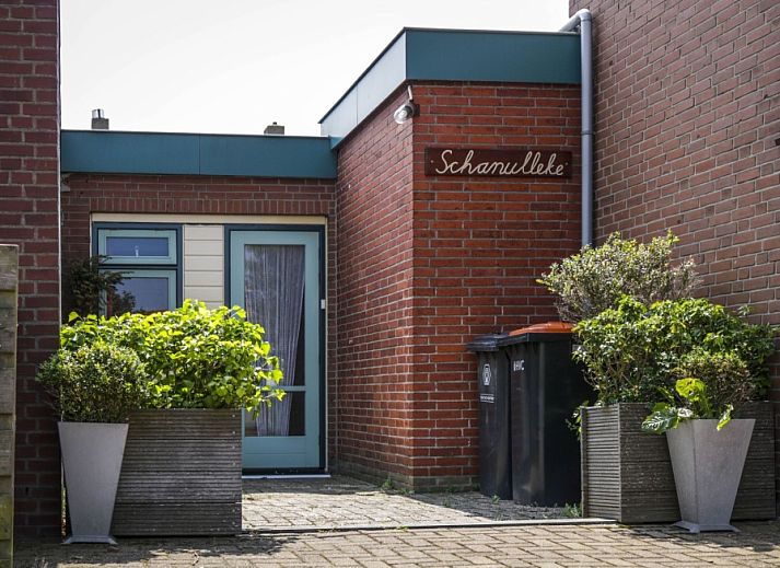 Entrance to vacation home Schanulleke in De Koog, Texel, with green plants and an inviting entrance.
