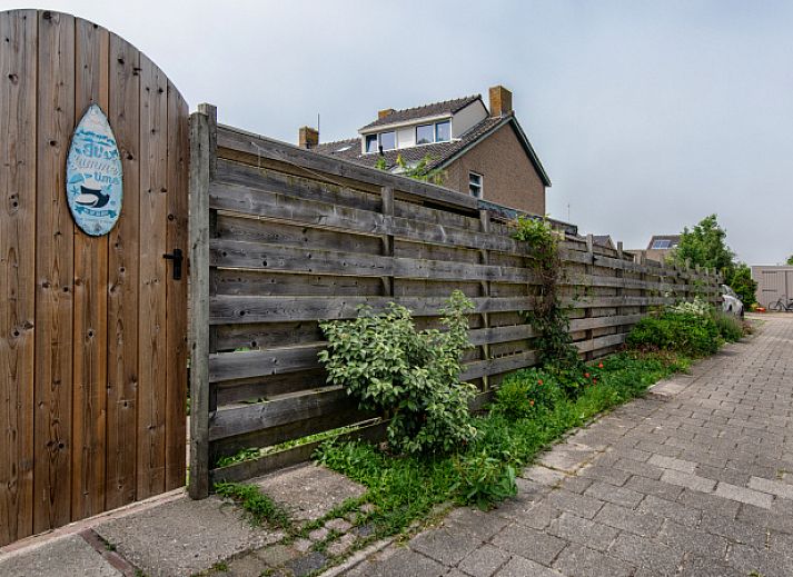 Geraeumige Terrasse am Ferienhaus 2490 in De Koog, Texel, umgeben von einem Holzzaun und bunten Blumen.