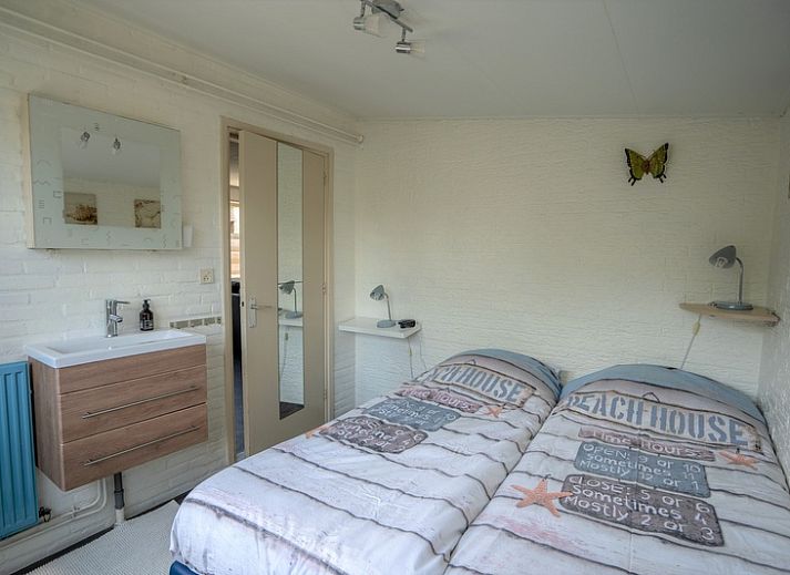 Geraeumige Terrasse am Ferienhaus 2490 in De Koog, Texel, umgeben von einem Holzzaun und bunten Blumen.