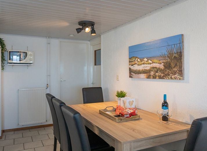 Gemuetliche Terrasse am Bungalow 1 in De Koog, Texel mit Gartenmoebeln und Sonnenschirm fuer ein optimales Leben im Freien.